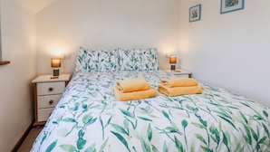 Ein Schlafzimmer mit einem Bett, zwei Nachttischen, zwei Wandbildern.