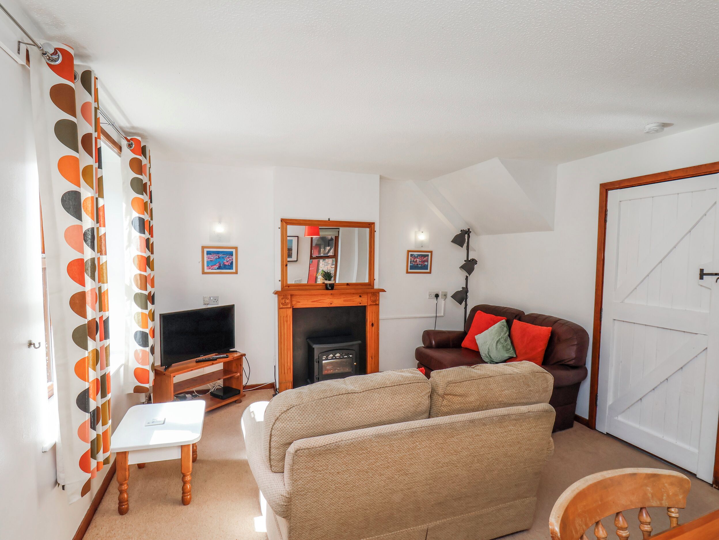 A living room with a sofa, a television, a fireplace, and a door.