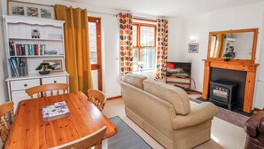 Ein Wohnzimmer mit einer Couch, einem Holzesstisch, einem Kamin und einem Bücherregal.