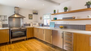 A modern kitchen with wooden cabinets, stainless steel appliances, and a wooden floor. - Estuary View (Morpeth)