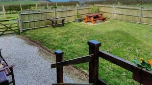 A fenced backyard with a picnic table and a wooden bench. - The Dovecote (Bideford)