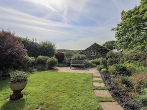 A stone house with a garden, a lawn, and a stone pathway leading to the house. - Kestrel Cottage (Grange-over-Sands)