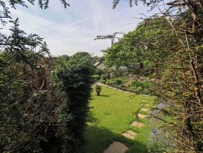 A garden pathway with a hedge on one side and a lawn on the other, leading to a stone wall. - Kestrel Cottage (Grange-over-Sands)