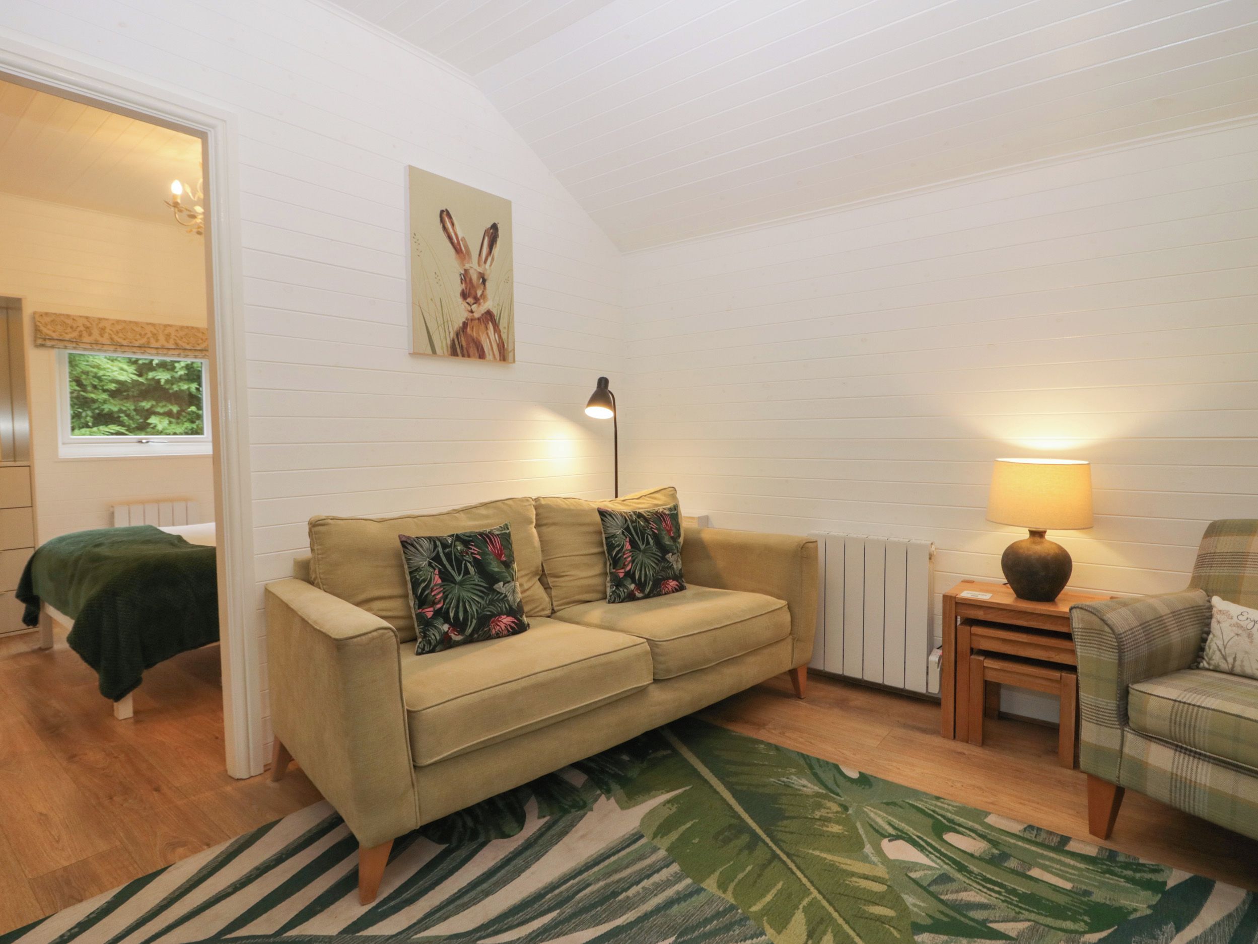 A cozy living room with a sofa, a small table, a lamp, and a painting on the wall.