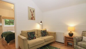 Un salon confortable avec un canapé, une petite table, une lampe et un tableau accroché au mur.
