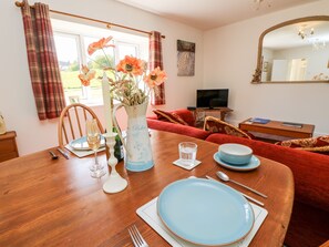 A dining table set with plates, cutlery, and a vase with flowers. - The Old Dairy (Newport)