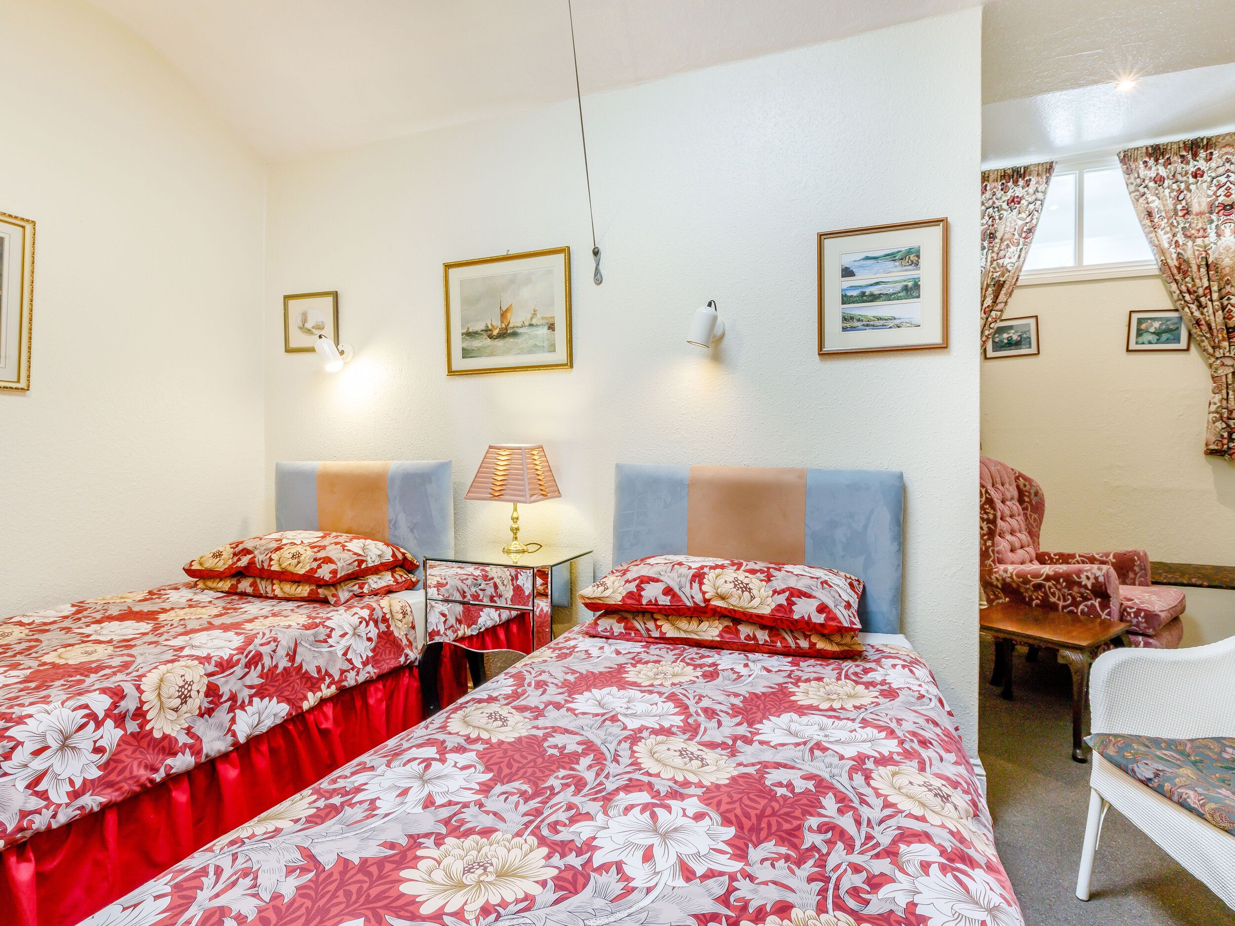 A hotel room with two beds, a desk, a chair, and a window with curtains.