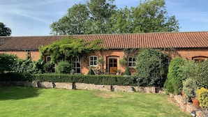 Una casa de totx amb teulada d'atells, envoltada d'un jardí ben cuidat i taronjades.