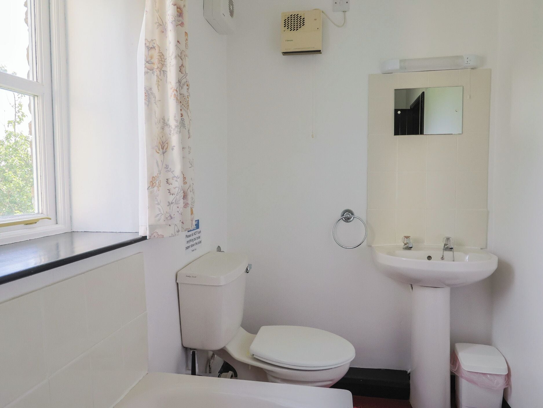 A small, basic bathroom with a toilet, sink, and a shower area.