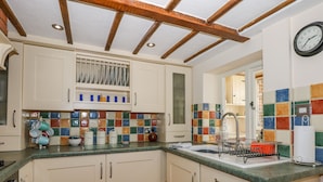 A kitchen with white cabinets, a tiled backsplash, and a wooden ceiling. - Holly Cottage (Swaffham)