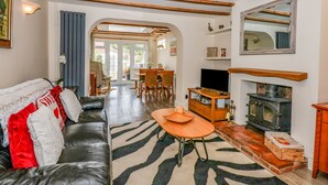 A cozy living room with a leather sofa, a wooden coffee table, and a fireplace. - Holly Cottage (Swaffham)