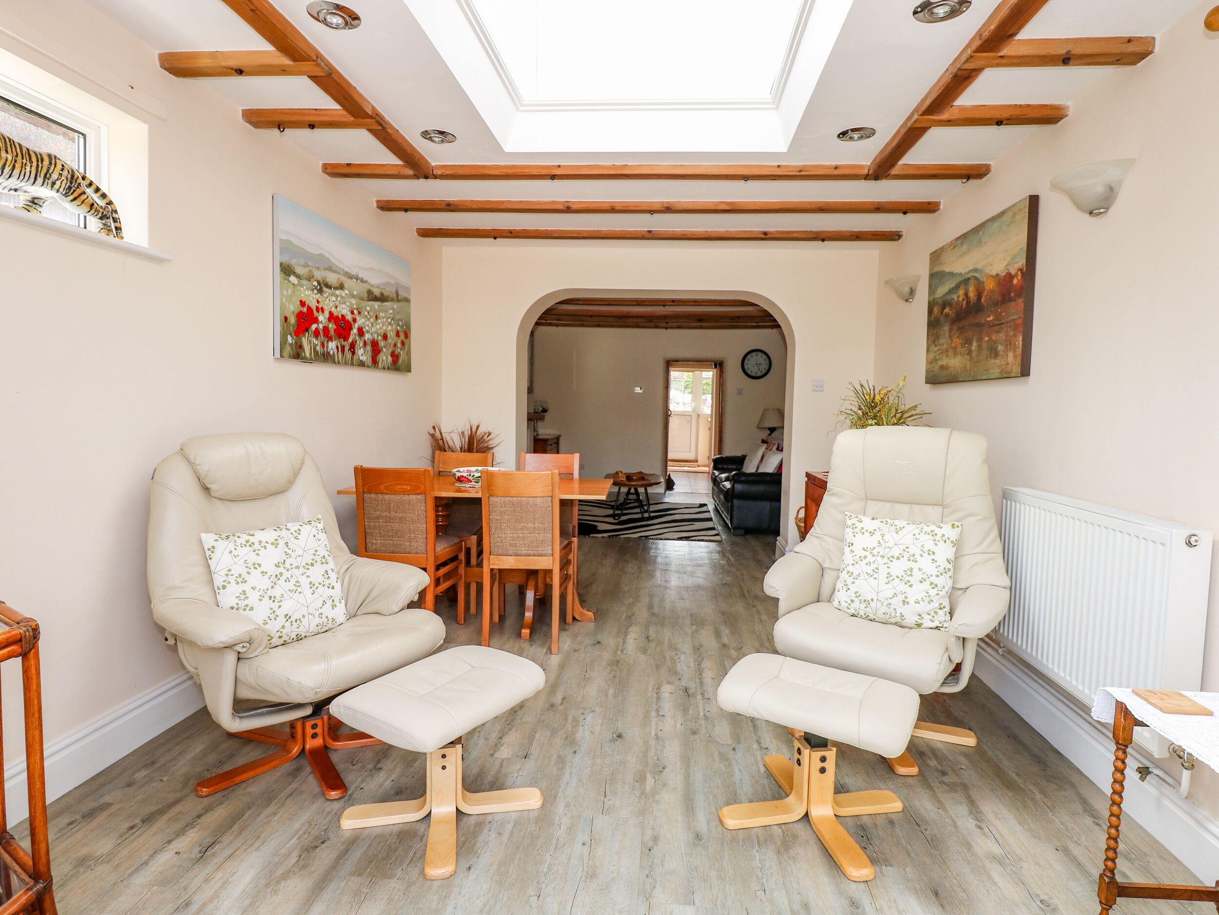 Amplia sala de estar con dos sillones de cuero, una mesa de comedor de madera y vista al área de comedor contigua.