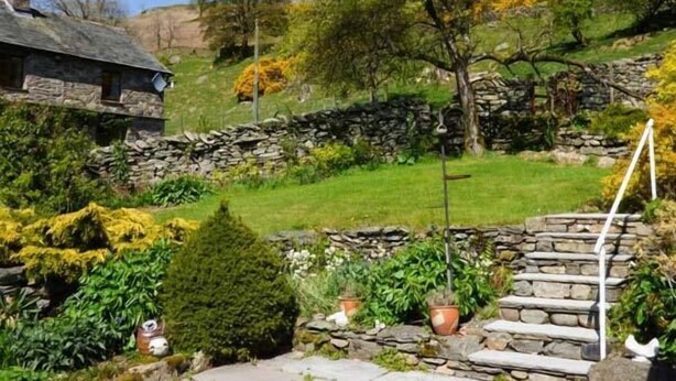 Une maison en pierre avec un escalier en pierre menant à un espace verdoyant.