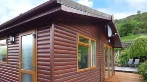 Une cabane en bois dotée de grandes fenêtres et d’une terrasse.