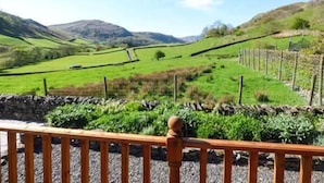 Vista panorámica de un valle verde con muros y cercas de piedra, probablemente parte de un paisaje rural.