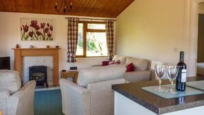 Una sala de estar acogedora con chimenea, un conjunto de sofás y un comedor con mesa y copas de vino.