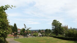 A park with a paved path, benches, and a statue. - Garden View (Malvern)