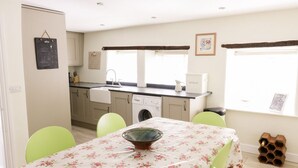Una cucina compatta con tavolo, sedie, lavatrice e una finestra vista.