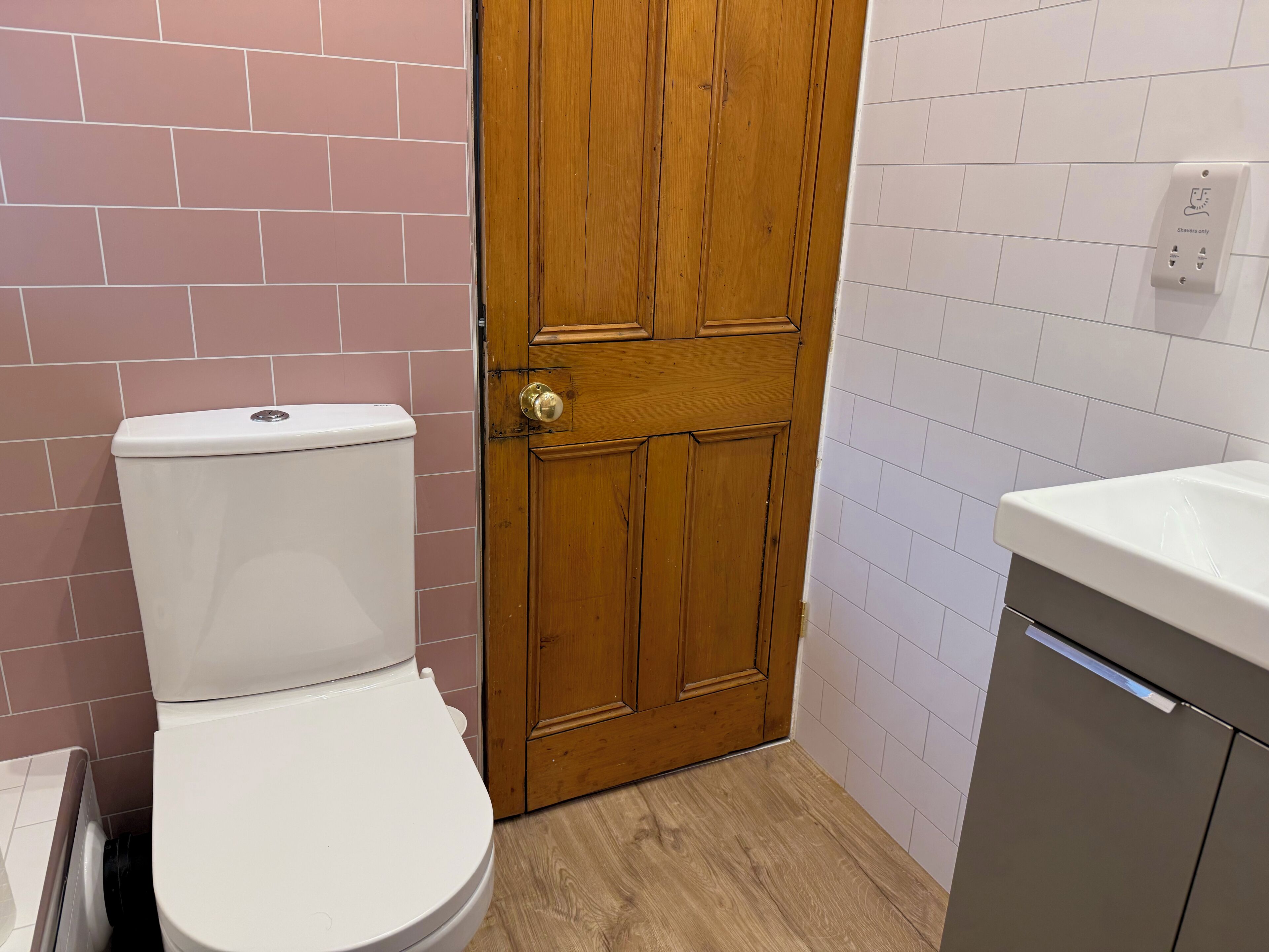 Un baño con inodoro, puerta de madera y lavabo.