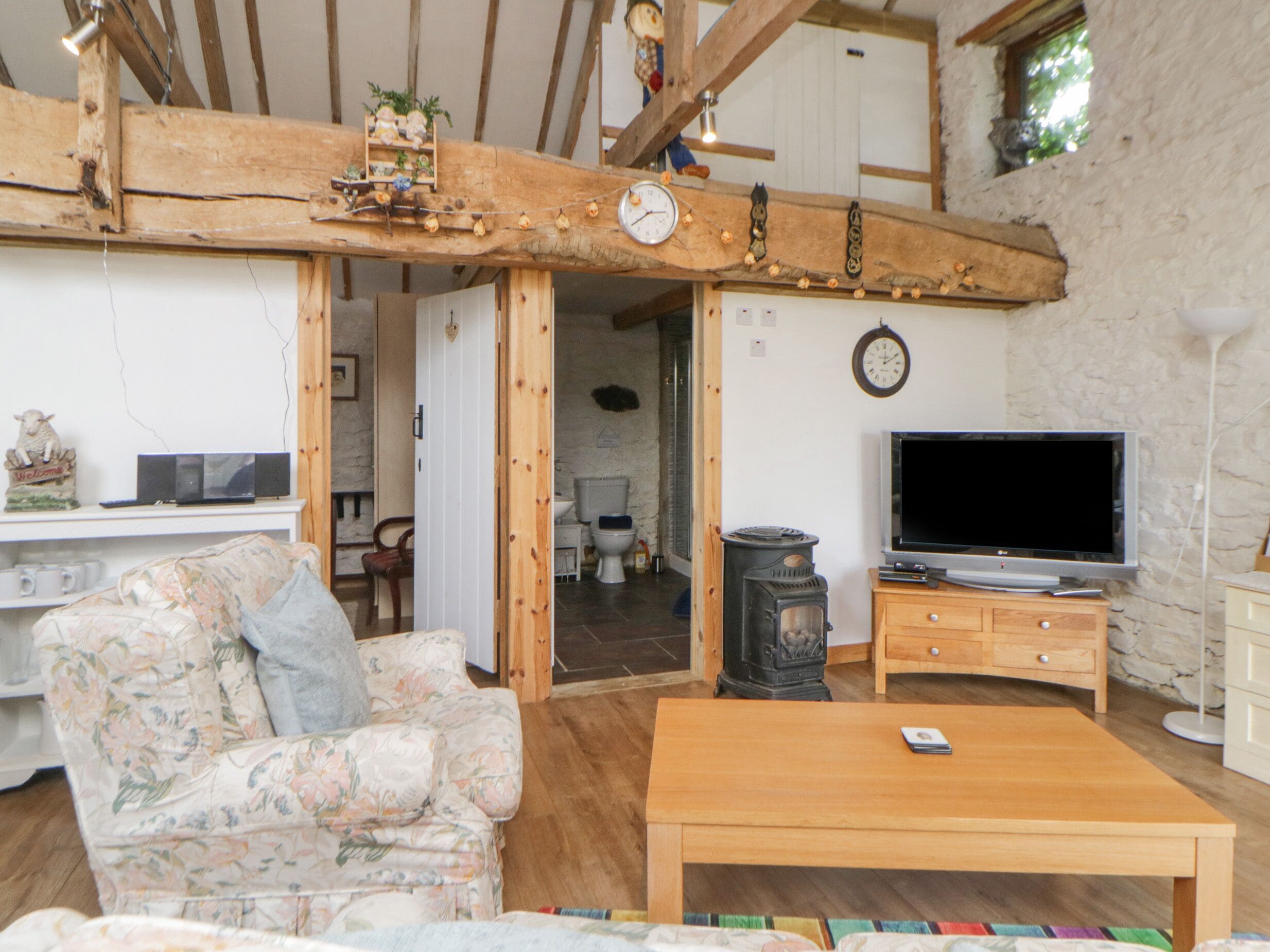 Un salon rustique avec un plafond en bois, un canapé, une table en bois, un téléviseur et une cheminée.