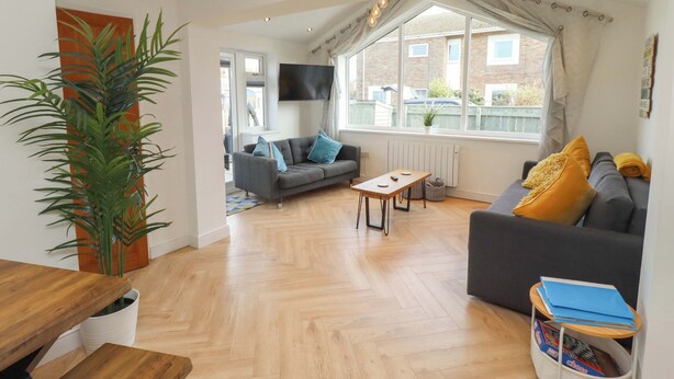 A modern living room with a sofa, a coffee table, and a TV. - Sunrise Cottage (Chathill)