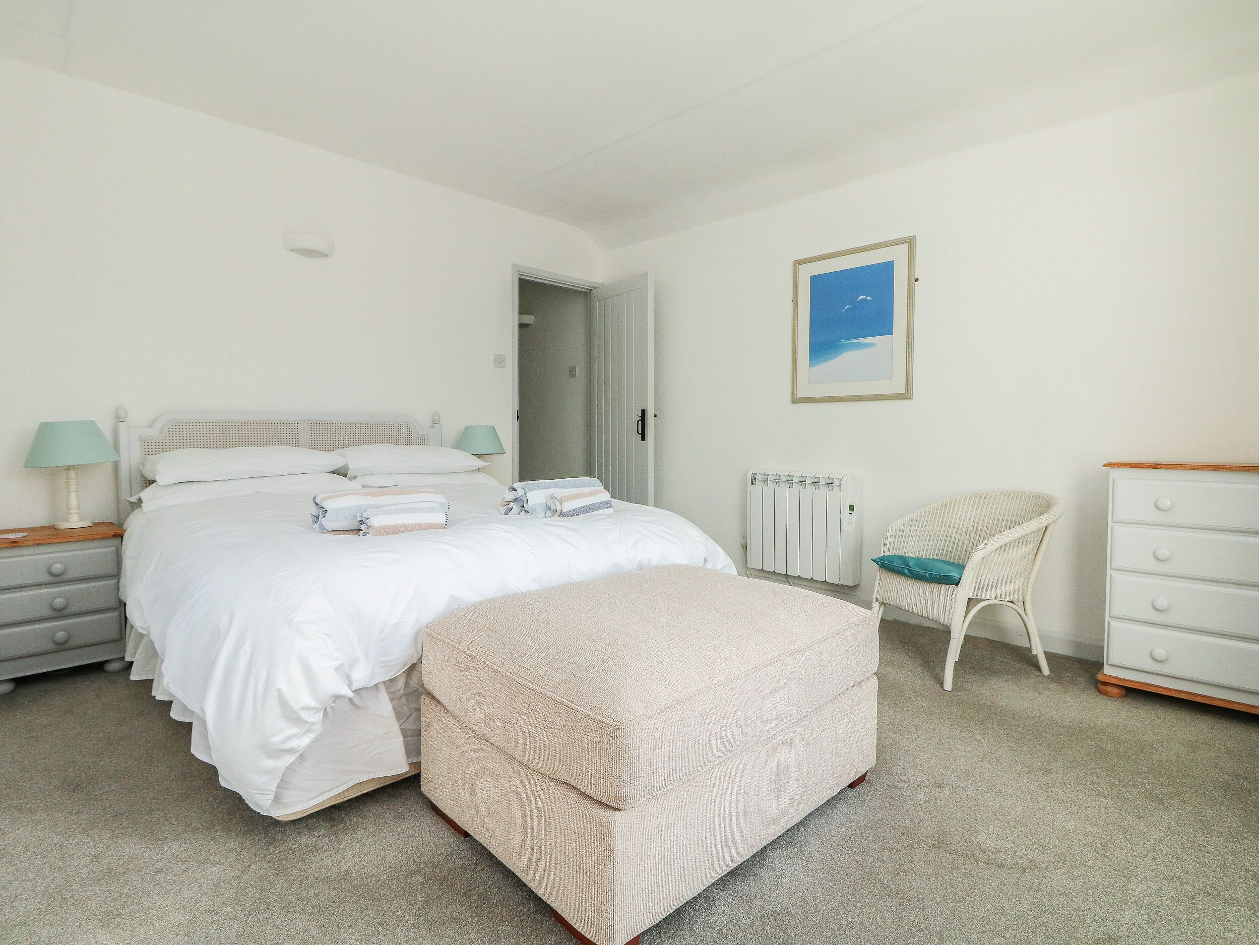 A bedroom with a bed, bedside tables, a chair, a dresser, and a radiator.