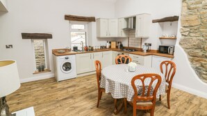 Uma cozinha compacta com máquina de lavar, armários de madeira e um espaço de refeições com mesa e cadeiras.
