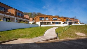 A modern building with a curved driveway leading to a gated entrance.