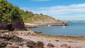 A rocky shoreline with a clear blue sky and calm sea.
