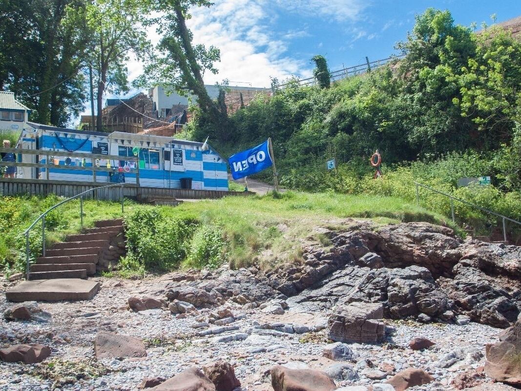 A blue and white boat docked near a rocky shore with steps leading up to it.