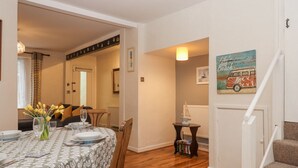 Un coin repas avec une table dressée pour quatre personnes, une bibliothèque et un escalier menant à un autre niveau.