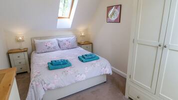 Un dormitorio con cama, dos mesitas de noche, un armario, una ventana y un cuadro en la pared.