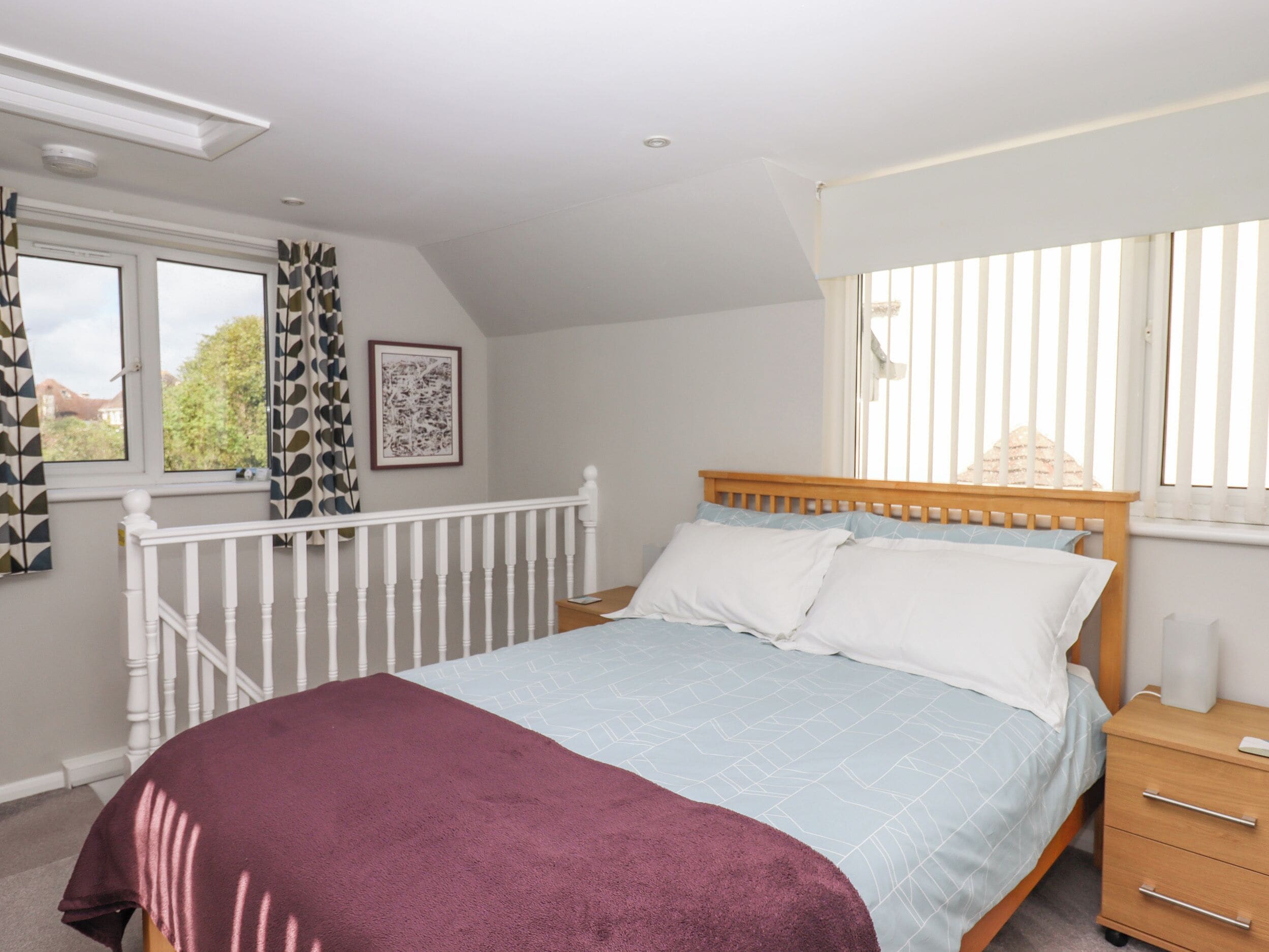 A bedroom with a bed, a nightstand, a window with curtains, and a ceiling light.