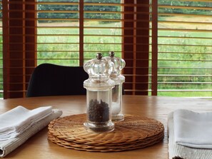 A table with a salt and pepper shaker set on a woven placemat, a folded white napkin, and a white cloth. - The Granary (Ross-on-Wye)