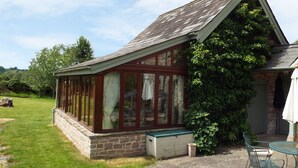 A conservatory with a stone base, glass walls, and a wooden roof. - The Granary (Ross-on-Wye)