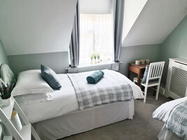 Un dormitorio con cama, escritorio, silla y radiador.