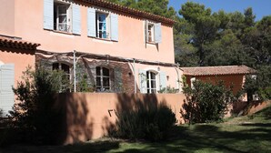 Ein zweistöckiges Haus mit Ziegeldach, zahlreichen Fenstern mit Fensterläden und einem gepflegten Garten.