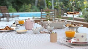 Frühstücksaufstellung mit Toast, Orangensaft und einer Obstschale am Pool.