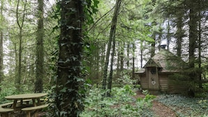 A rustic wooden cabin in a forest with a picnic table nearby. - The Cottage at Graysondale Farm (Cockermouth)