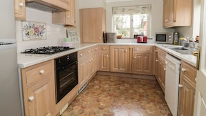 A kitchen with wooden cabinets, a gas stove, a microwave, and a sink. - The Lodge off High Street (Ipswich)