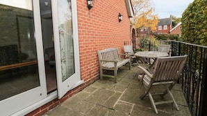 A patio with a brick wall, a glass door, and a table with chairs. - The Lodge off High Street (Ipswich)