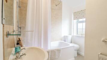 Een badkamer met een bad, toilet en wastafel.
