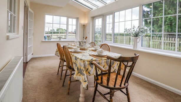 Une salle à manger avec une table dressée pour six personnes, de grandes fenêtres et une vue sur l’extérieur.