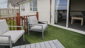 Une pièce dotée d’une porte-fenêtre coulissante donnant sur un balcon, d’une petite table et de deux chaises.