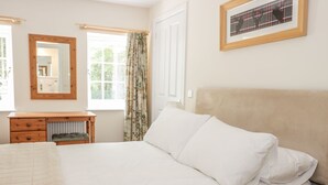 A bedroom with a bed, a nightstand, a dresser, and a window with curtains. - East Lodge (Walkerburn)