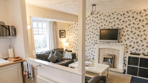 Ein gemütliches Wohnzimmer mit Kamin, Fernseher und einer bequemen Sitzecke.
