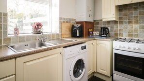A kitchen with a washing machine, a stove, and a coffee maker. - Mousehole Cottage (Carlisle)