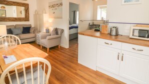 A compact living space with a kitchenette, a dining area, and a bedroom. - Wren Cottage (Ilfracombe)