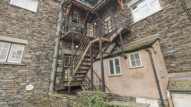 Ein mehrstöckiges Steinhaus mit einer zentralen Treppe und einem Schild für private Parkplätze.