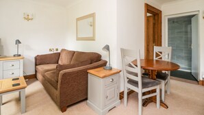 A compact living space with a sofa, a small table, a chair, and a cabinet. - Thirlmere Suite (Keswick)
